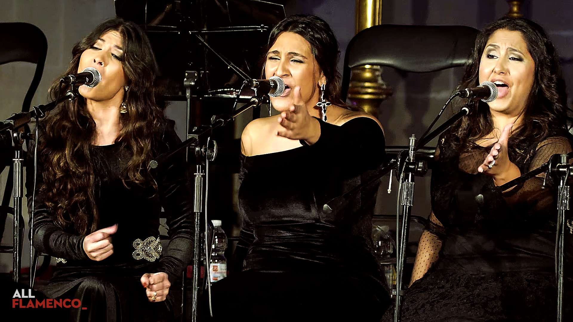 黒い衣装の3人の歌い手がマイクの前に座って歌う、『Así canta Jerez en Navidad』の一場面